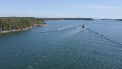 small speed boat approaching tug boat wakes in finnish archipelago