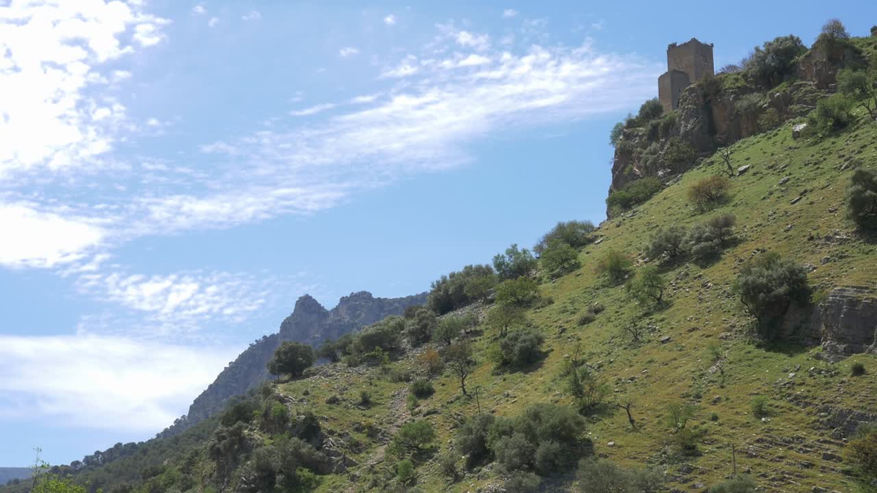 View of Otiñar Castle, a ruined medieval fortress, framed by a large rocky mountain
