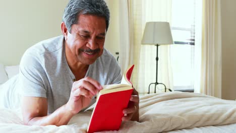 senior man reading a noel in bedroom 4k