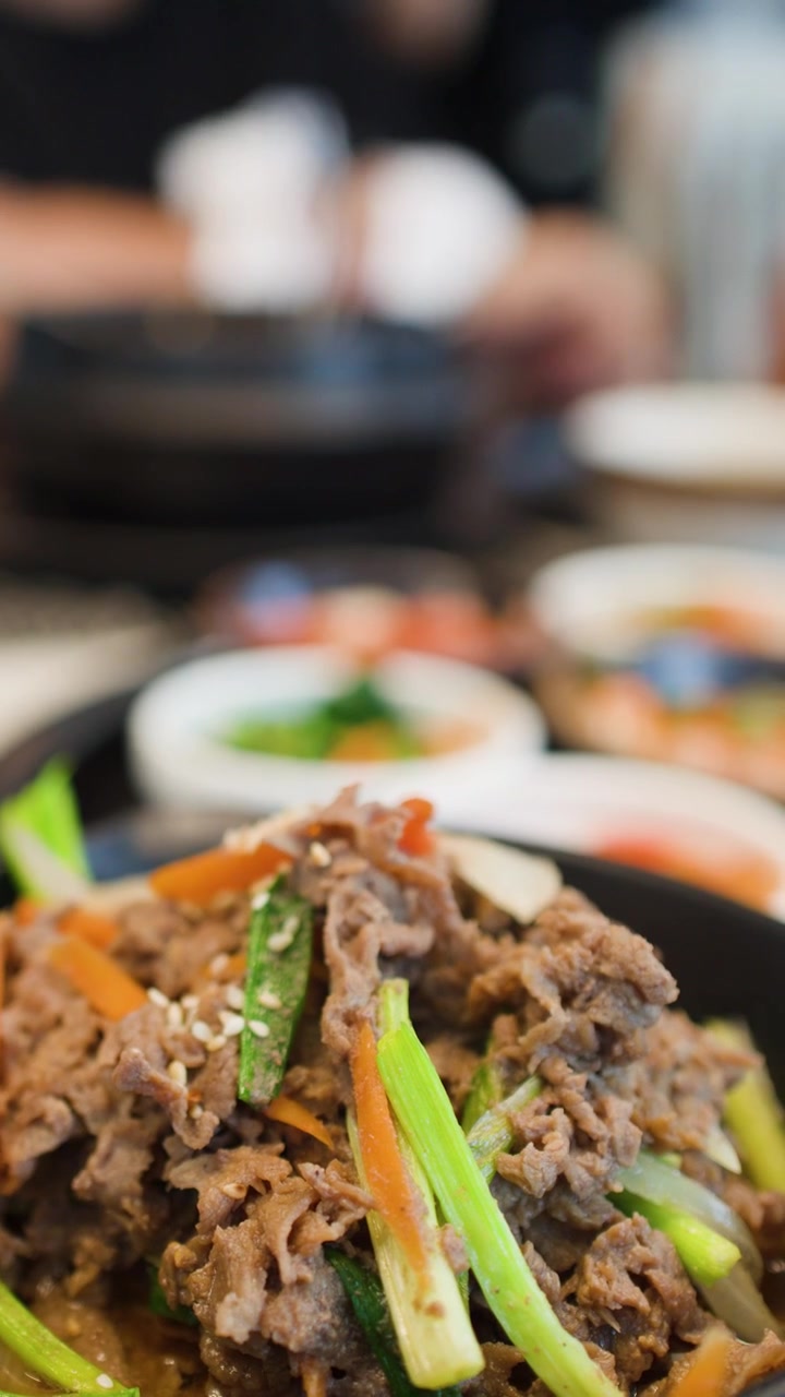 Tangkapan close-up bulgogi daging sapi Korea yang mengepul disajikan dengan berbagai lauk tradisional