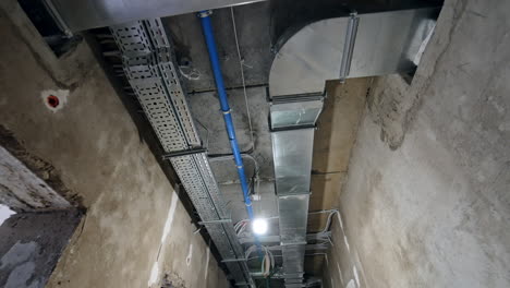complicated system of pipes of metal and plastic on the ceiling of the long corridor. old building renovation concept. low angle view.