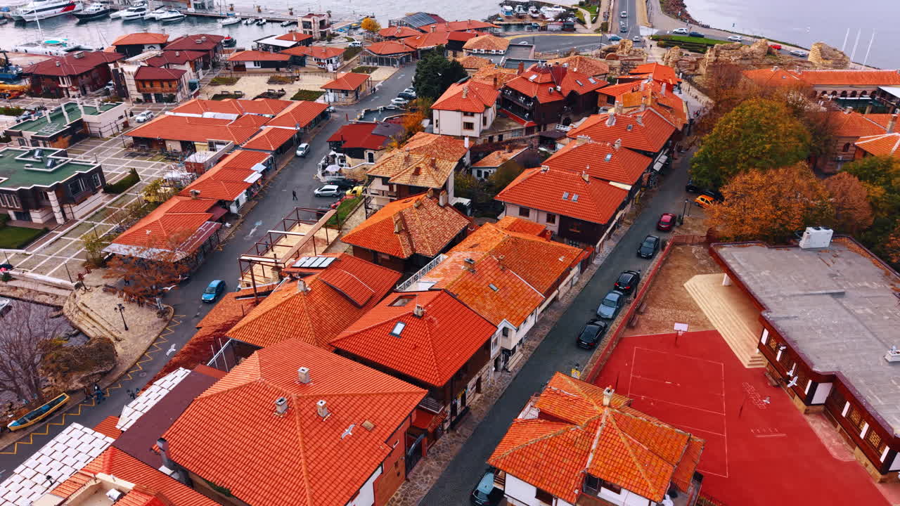 Vista aerea di strade cittadine e tetti rossi. Ripresa con drone di architettura di una città europea caratterizzata da tetti di tegole arancioni, strade acciottolate e un campo sportivo rosso.