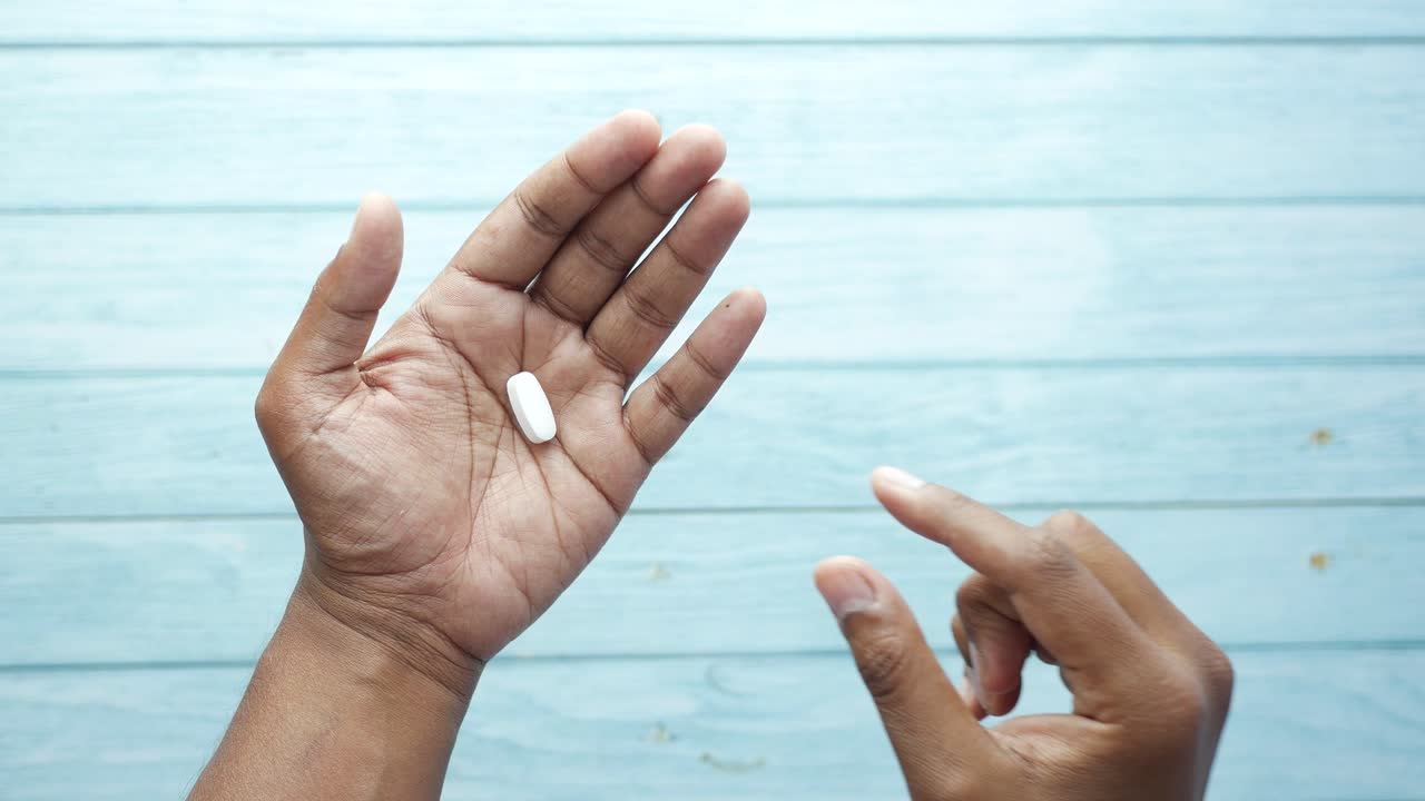 persona que sostiene una píldora blanca