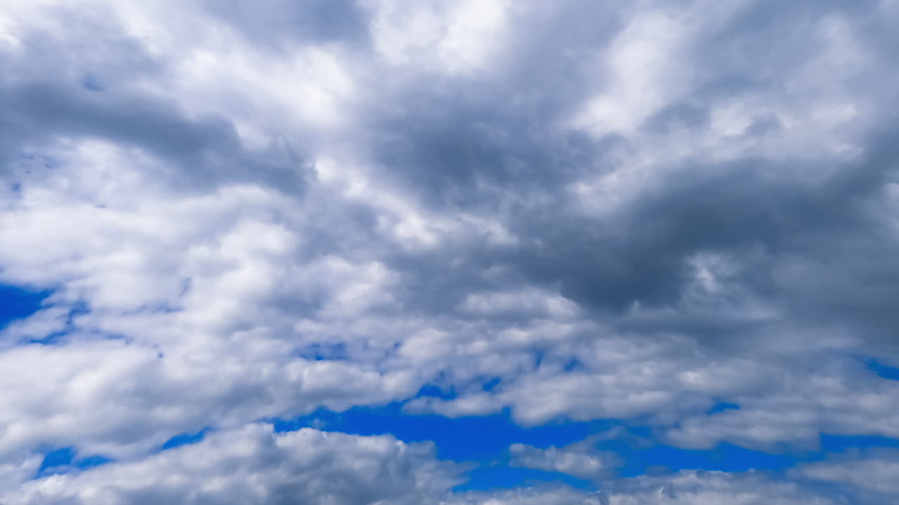 Heavy dramatic clouds float quickly by the sky. Low angle view on the rainy cloudscape in atmosphere. Timelapse.