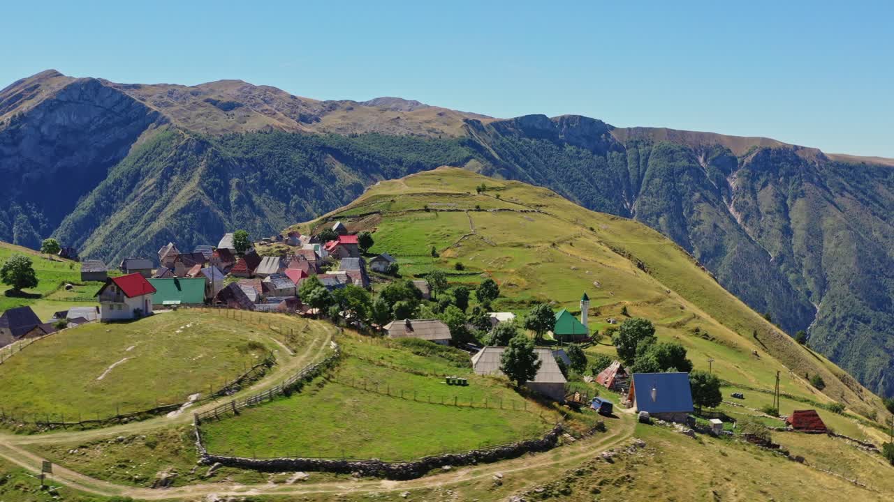 Charming village and rural fields on mountain top, Bosnia. Aerial arc shot