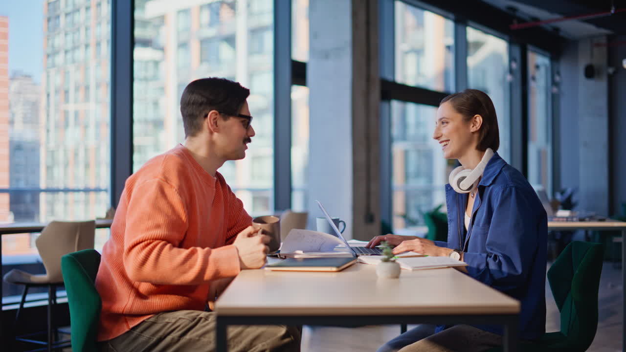 Smiling workers drinking coffee at creative office space. Happy two colleagues