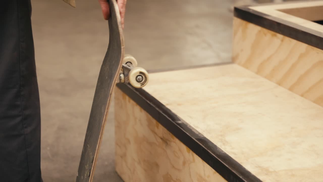 slowmo filmado con una sección baja de un adolescente irreconocible en vaqueros caminando más allá de la cámara y recogiendo su patineta con el truco de recoger la nariz