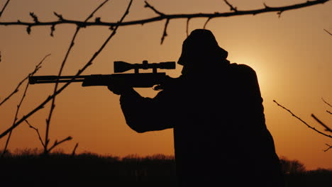 Silhouette-Of-A-Hunter-With-A-Gun-The-Sun's-Rays-Shine-In-His-Face