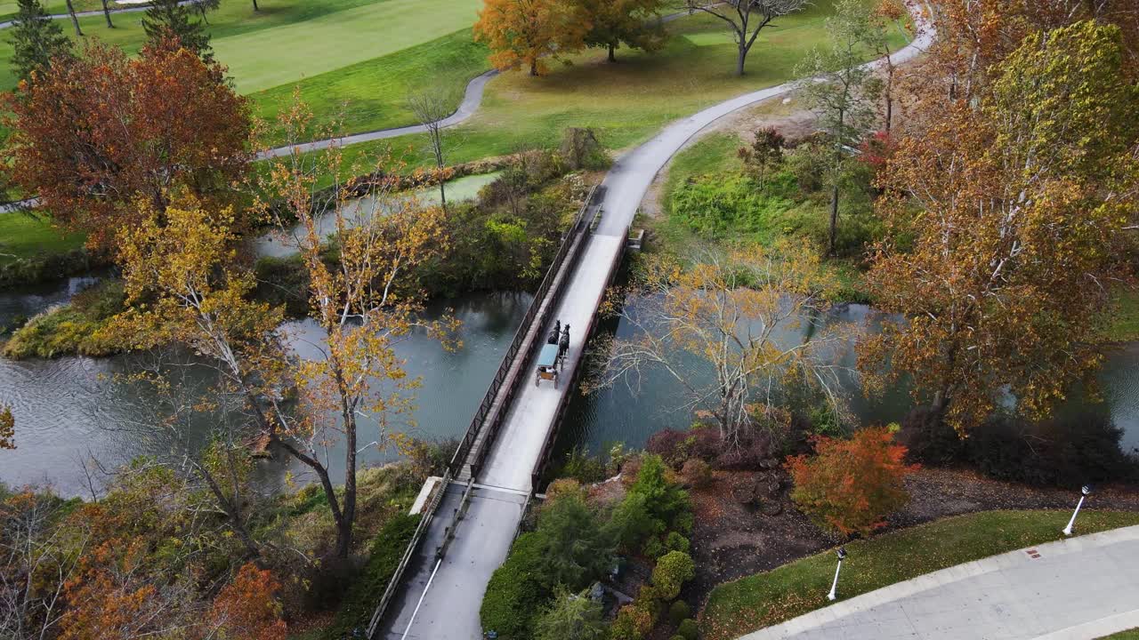 toma aérea de un carruaje tirado por caballos sobre el puente en el greenbrier durante el otoño