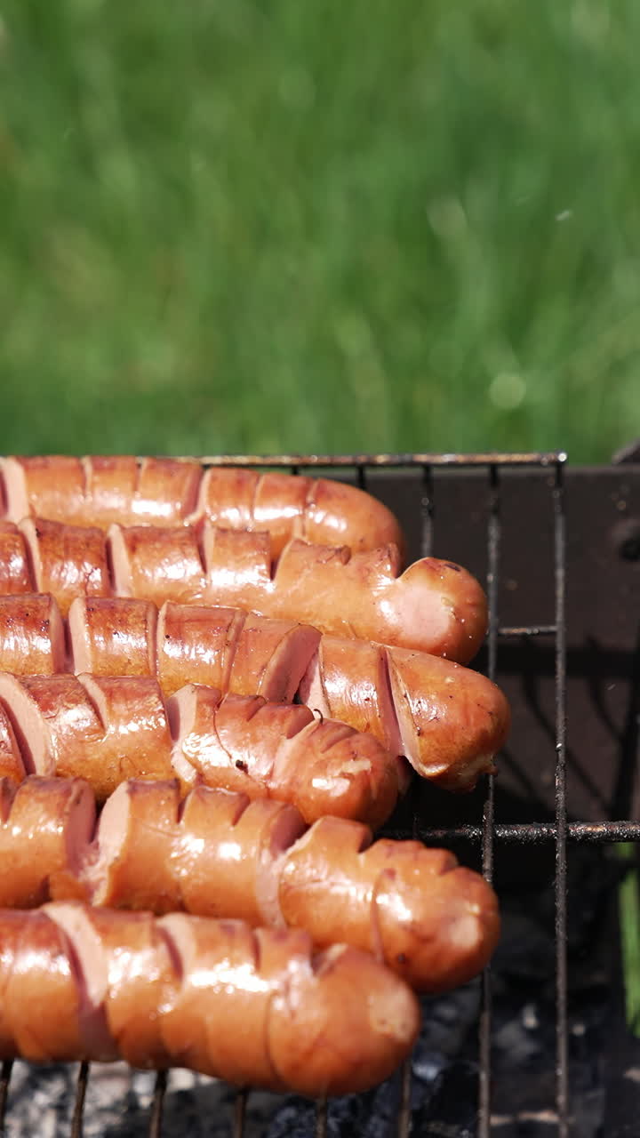 Sausages grilling on the barbecue. Juicy sausages frying on a fire. Hot delicious meat. Vertical video