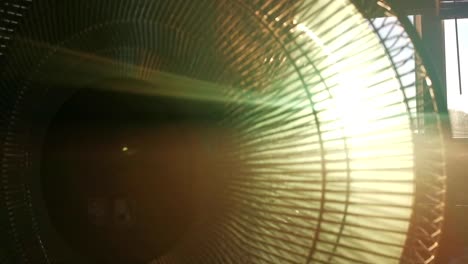 dusty indoor fan during sunset. low sun breaking through grid and propellers of ventilator causing lens flares.