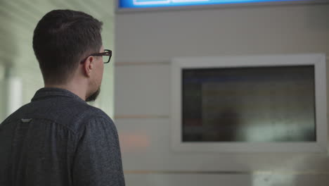 hombre mirando una pantalla de información del aeropuerto