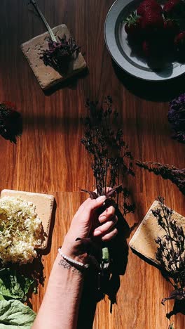 la mano sosteniendo flores con bayas en la mesa de madera