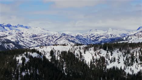 the stunning winter spring snowy jagged towering peaks of the minarets summit mountains mammoth lakes california aerial drone sunny clouds daytime deep backcountry deep snow vista point pan left