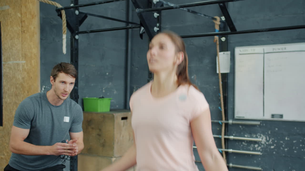 Woman jumping rope with a trainer in a gym