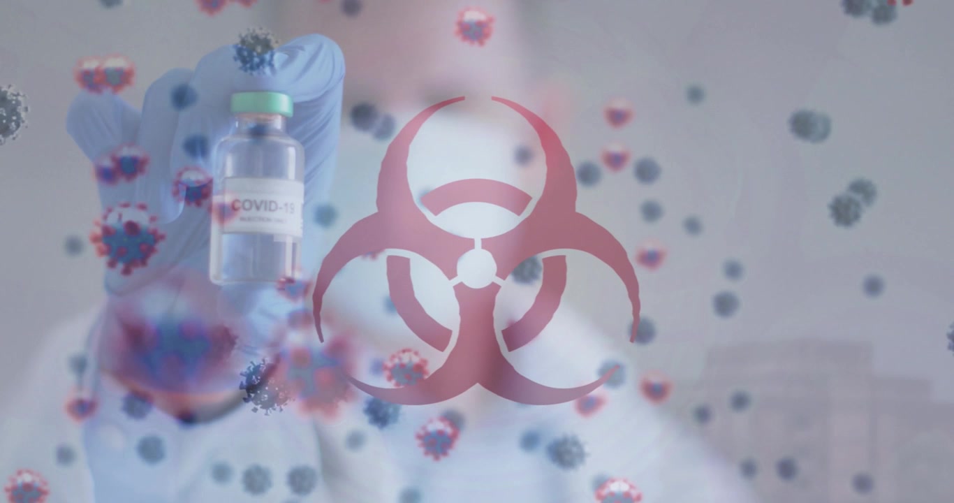 Animation of virus cells and biohazard over caucasian male doctor in face mask holding vaccine