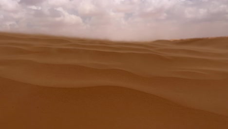 sand blowing over desert dunes on windy day in tunisia