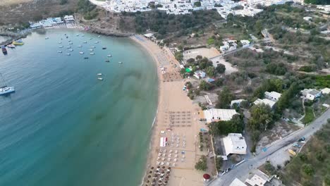 Aerial-footage-of-Lindos-beach,-the-Acropolis-of-Lindos-above-Lindos-town-at-sunrise