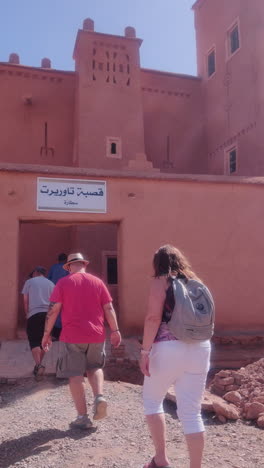 people walking towards entrance of kasbah amridil in skoura, morocco. vertical shot