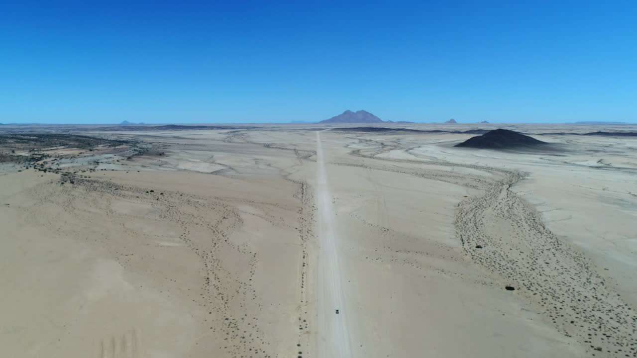 Aerial of a jeep driving to spitzkoppe in Nambia surrounded by desert.