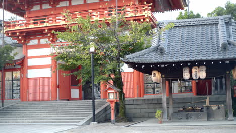 Water-pouring-out-of-a-bamboo-stick-into-a-carved-stone-in-front-of-a-big-shrine-in-Kyoto,-Japan-soft-lighting