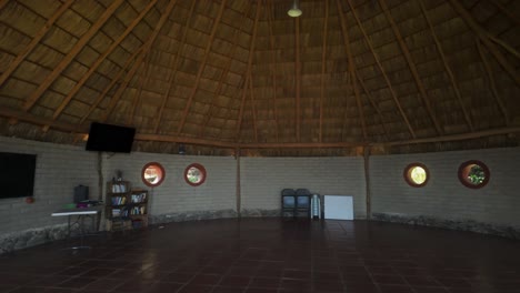 a cozy interior of a thatched-roof hut with circular windows - pan right shot
