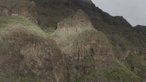 Impressive-volcanic-rock-face-with-sunstripe-and-misty-clouds-forming