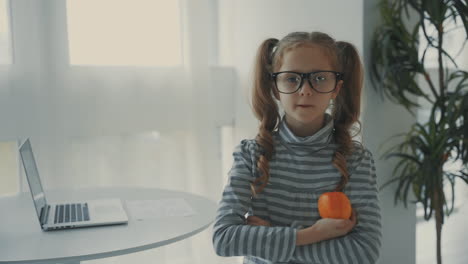 little girl with glasses holds a fruit