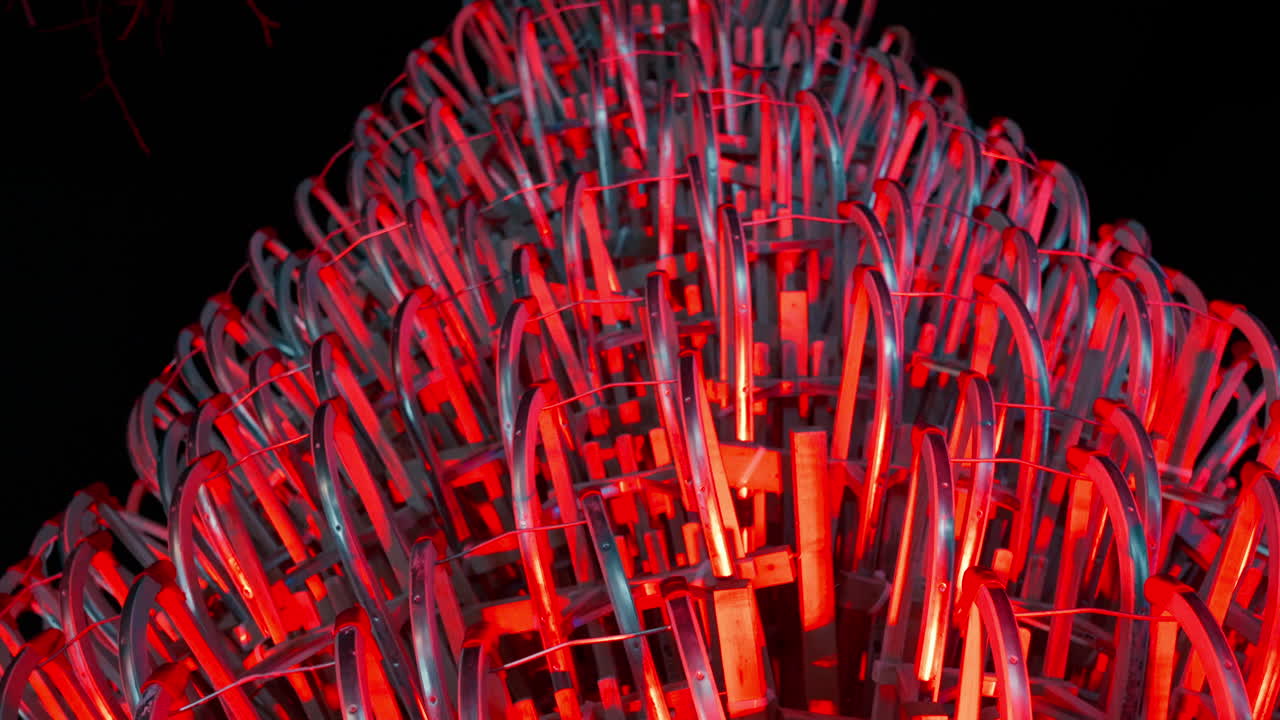 gran árbol de navidad hecho de trineos iluminado con luces rojas durante una noche en un campus universitario del mercado de navidad en viena, austria