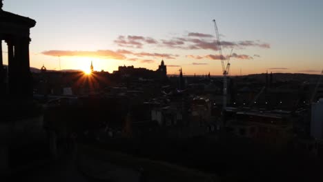 Calton-Hill-Sonnenuntergang-In-Edinburgh-Schottland-Mit-Sonne-Starrt-Am-Horizont-über-Edinburgh-Castle-Und-Gebäuden-In-Einer-Silhouette