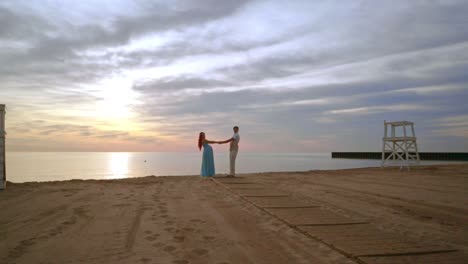 Pregnant-couple-dancing-on-sea-beach-at-sunset.-Happy-couple.-Expecting-parents