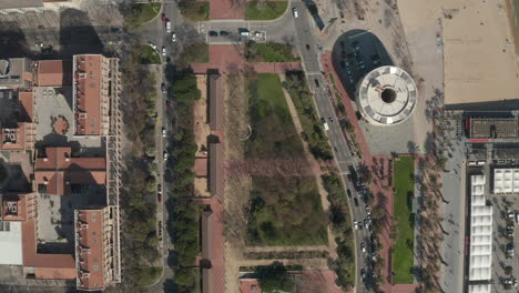 Building-and-transport-infrastructure-from-height.-Top-down-shot-of-vehicles-driving-on-road-along-coast.-Barcelona,-Spain