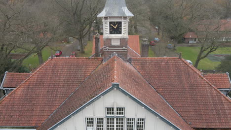 high jib up of old manor with clock tower overseeing small town in autumn