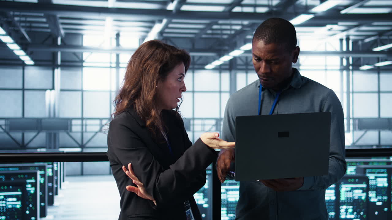 Developers in data center workspace coding on laptop, analyzing metrics