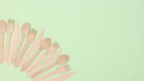 una pila de utensilios de cocina ecológicos y sin residuos bailan y se mueven sobre un fondo verde claro.