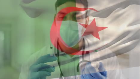 Animation-Der-Flagge-Algeriens,-Die-über-Einem-Arzt-Weht,-Der-Eine-Gesichtsmaske-Trägt-Und-Einen-Impfstoff-In-Der-Hand-Hält