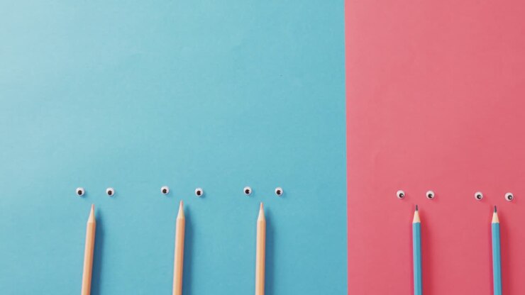 Video of composition with crayons and eyes on blue and pink surface