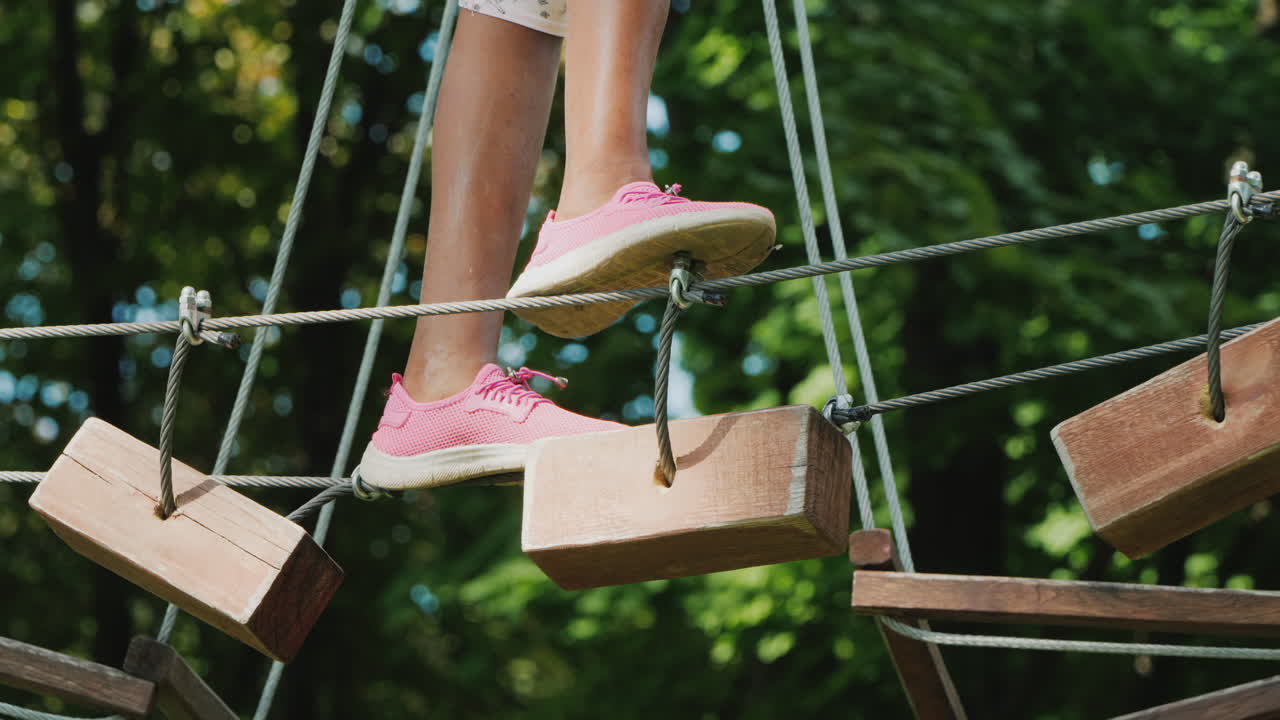pies de un niño afroamericano caminando por un cable estirado entre árboles