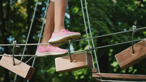 pies de un niño afroamericano caminando por un cable estirado entre árboles