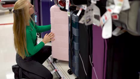 closeup of pretty mature woman looking at travel luggage in a store display