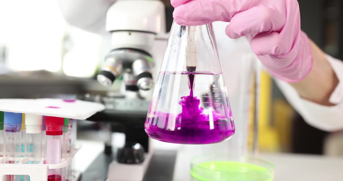 Una solución púrpura se arremolina en un matraz con agua durante pruebas de laboratorio.