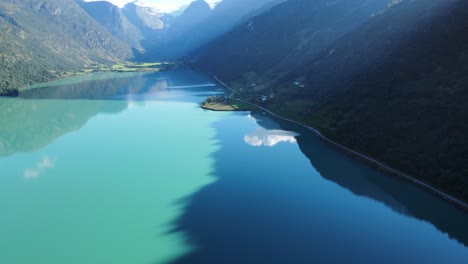 lago glaciar oldevatnet en noruega con agua verde, reflejo de nubes y montañas en él