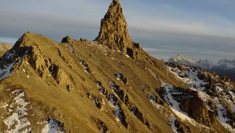 aerial orbit climbing around rocky summit, alpine landscape in the background