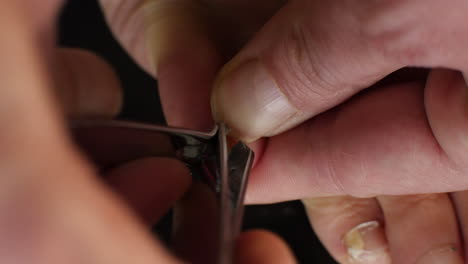 macro shot of a pinky toenail with fungal infection being clipped against a black background
