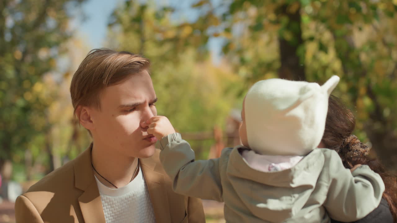Padre e bambino che si godono l'aria aperta. Genitori felici con il loro neonato durante un vivace pomeriggio autunnale. Padre e madre spensierati che condividono momenti speciali con il loro bambino in un contesto di parco colorato.