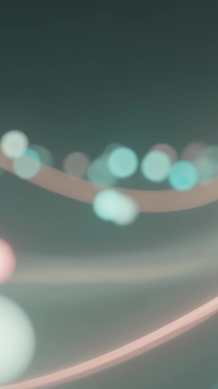Vertical video: Pulsing teal pink orbs drifting right across teal backdrop, forming curved trail