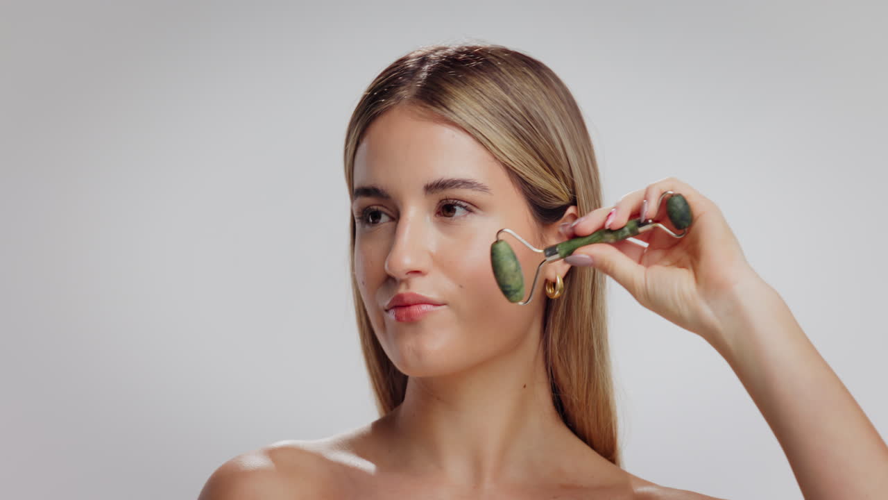 Kvinde bruger en jade-roller til ansigtsmassage
