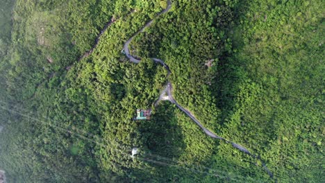 Vista-Aérea-De-Una-Estrecha-Y-Sinuosa-Carretera-De-Montaña-Rodeada-De-Una-Exuberante-Naturaleza-Verde