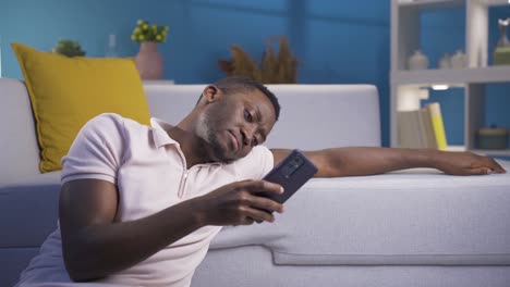 Depressed-and-unhappy-African-young-man-using-his-smartphone.