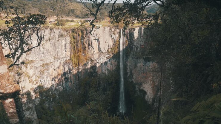 Veduta attraverso la foresta pluviale di una grande cascata a parete rocciosa situata a Urubici, Santa Catarina, Brasile.